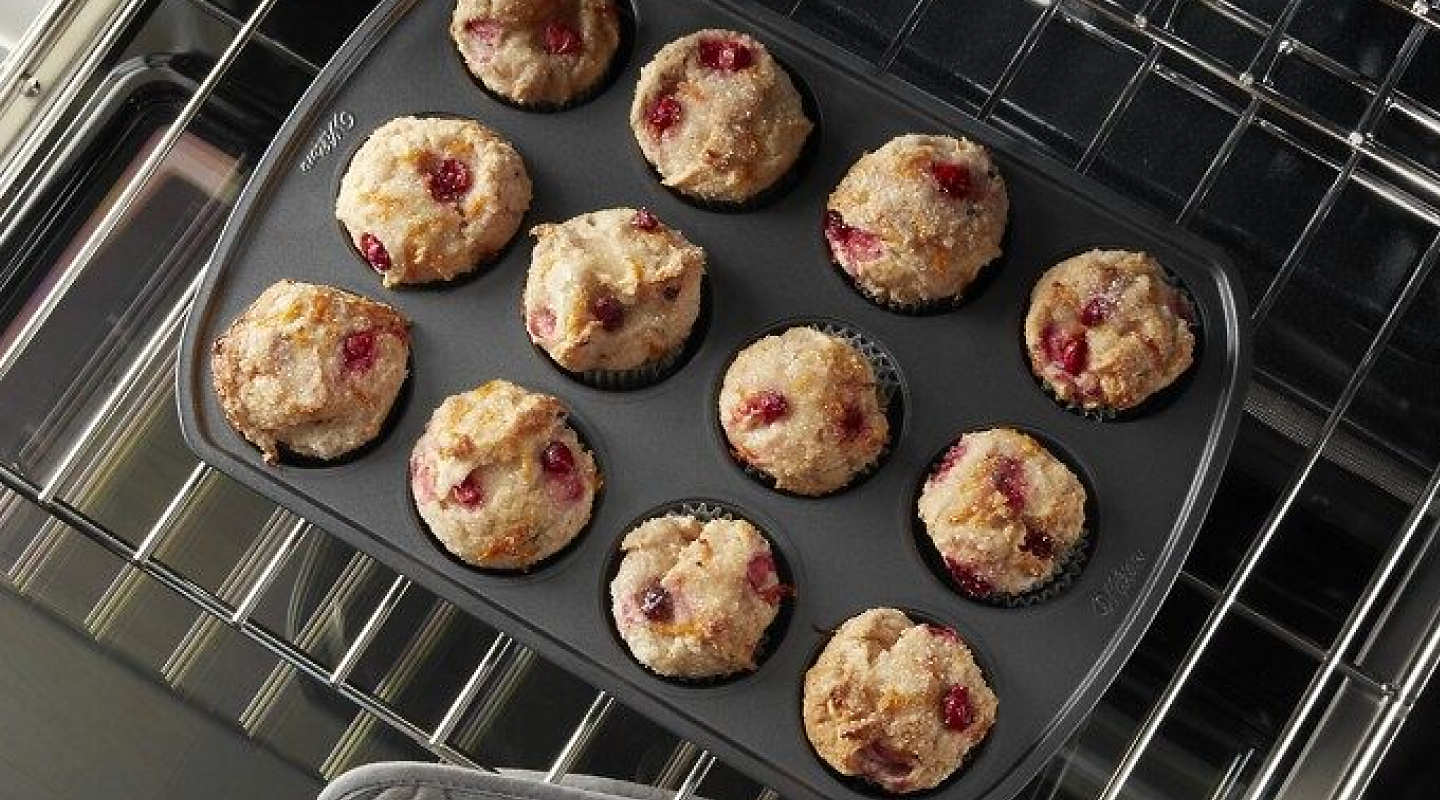 Overhead view of berry muffins baking on an oven rack.