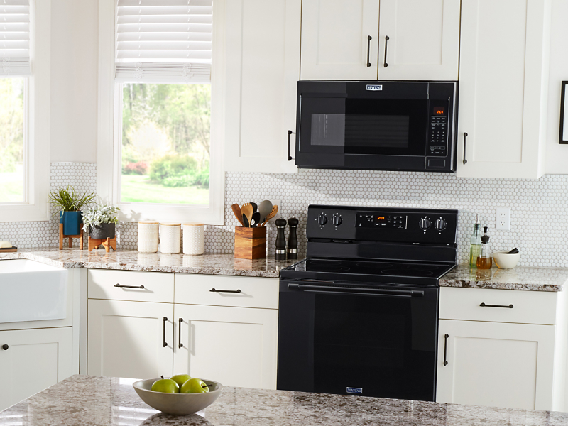 Black Maytag® over-the-range microwave over a black range in a classic kitchen