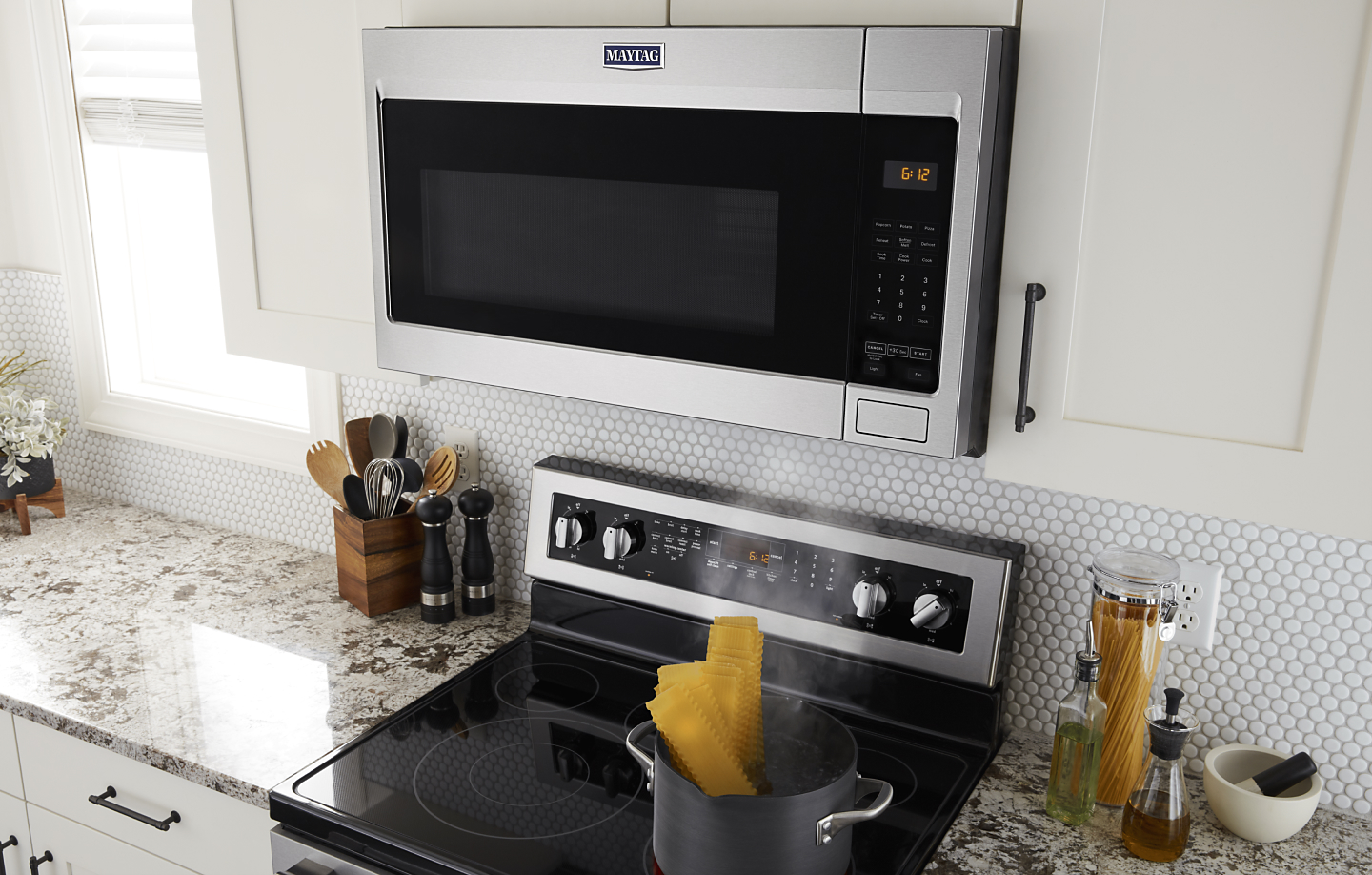 Maytag® over-the-range microwave above a Maytag® range set in white cabinetry