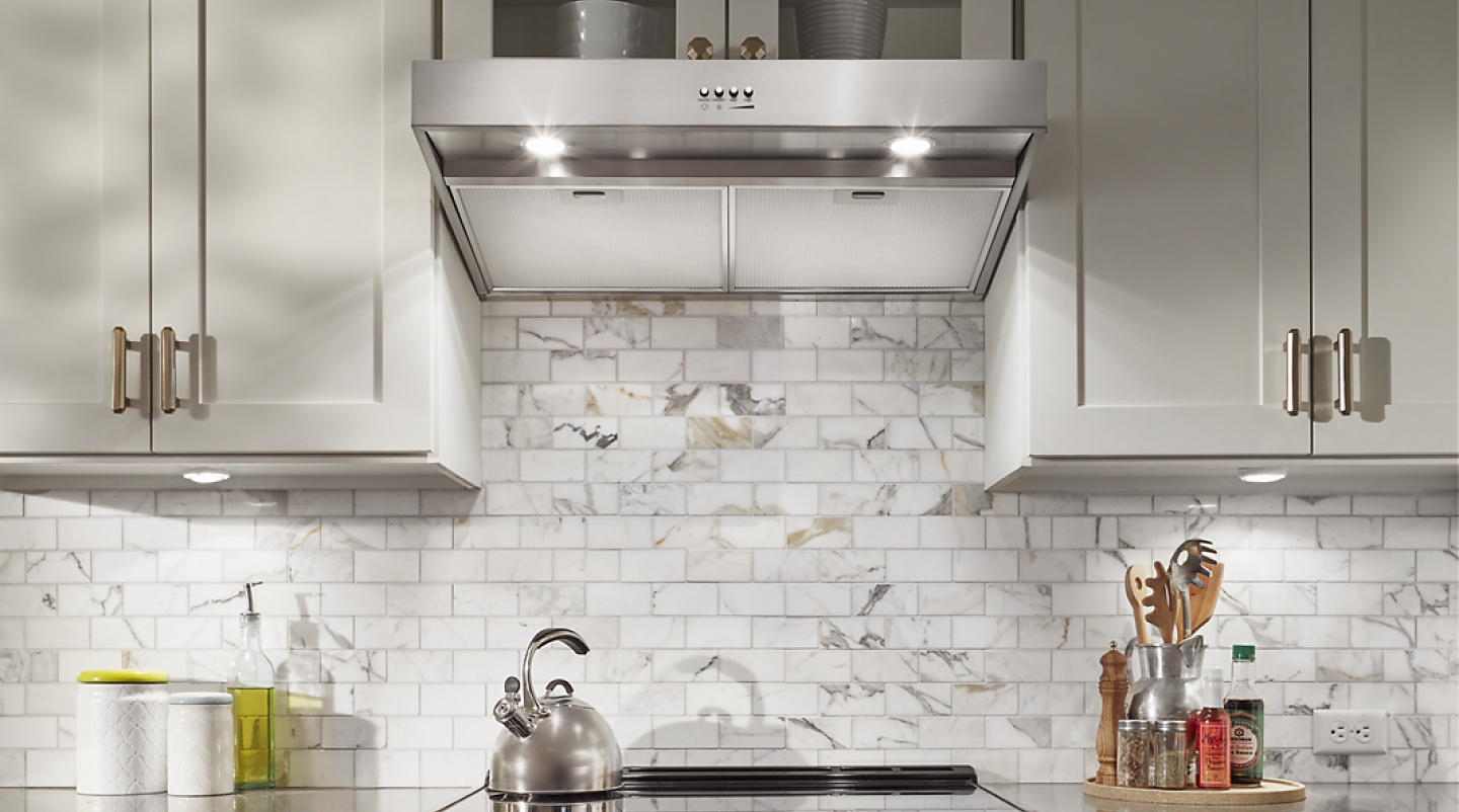 Wall mount flat range hood in white cabinetry.