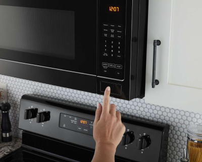 Hand pressing a button to open the microwave
