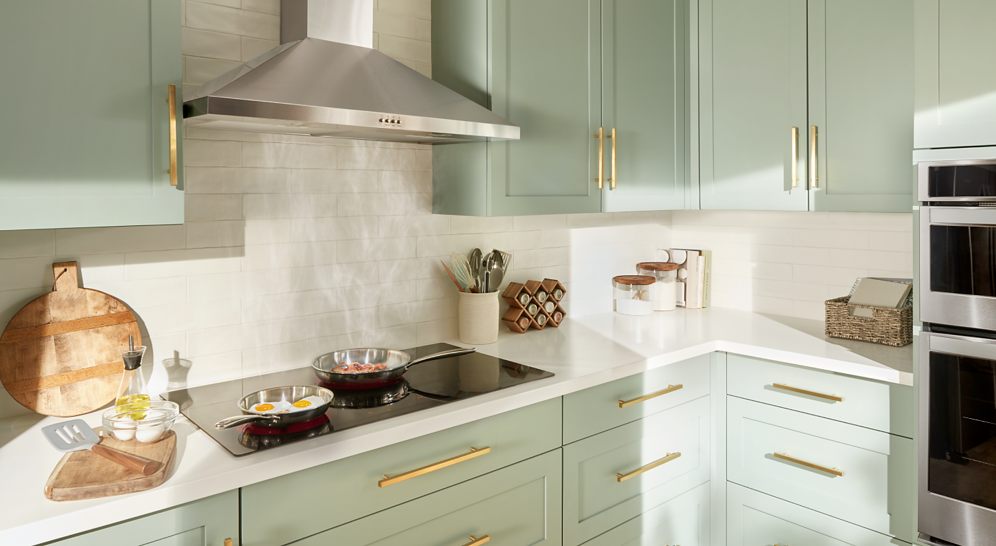 Stainless steel Maytag® range hood in a light green kitchen