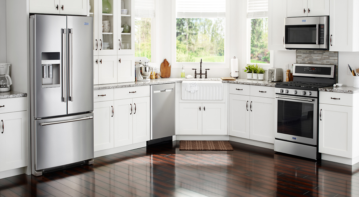 Various stainless steel appliances in a modern kitchen with white cabinetry 