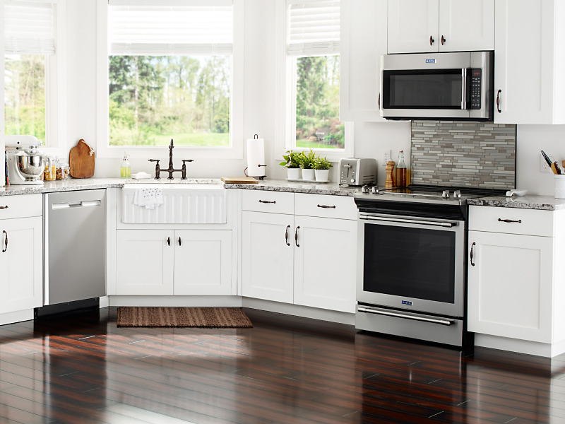 Various stainless steel appliances in a kitchen with white cabinetry