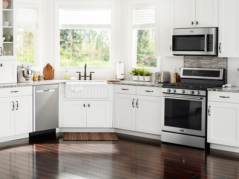 Various stainless steel appliances in a modern kitchen with white cabinetry 