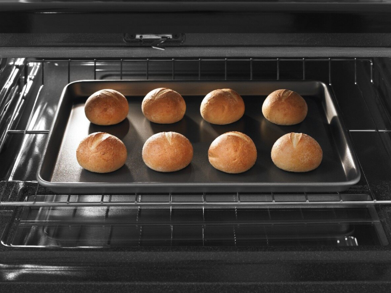 Small bread loaves on a baking sheet and in an oven