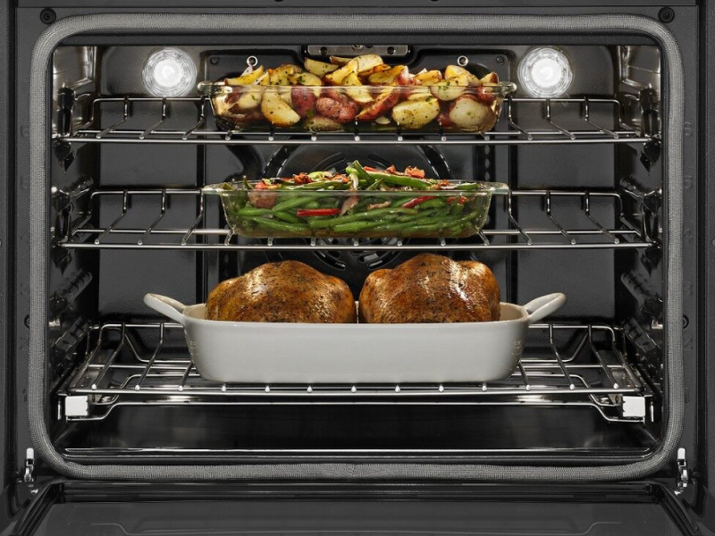 Various foods cooking in an oven on multiple racks