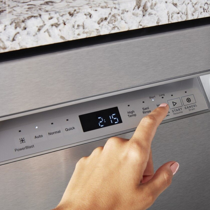 Hand touching a button on a front control dishwasher control panel