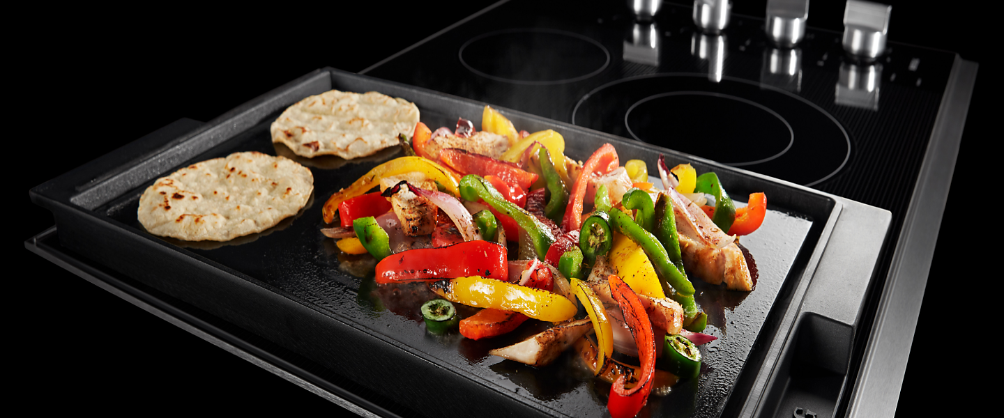Fajitas cooking on an electric cooktop with a griddle