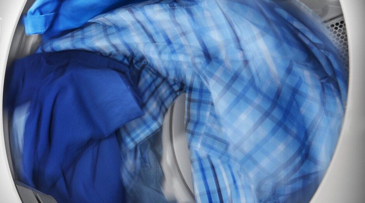 Blue clothing tumbling inside of a dryer.