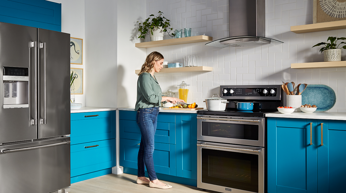 Woman prepping food in colorful kitchen with a modern hood