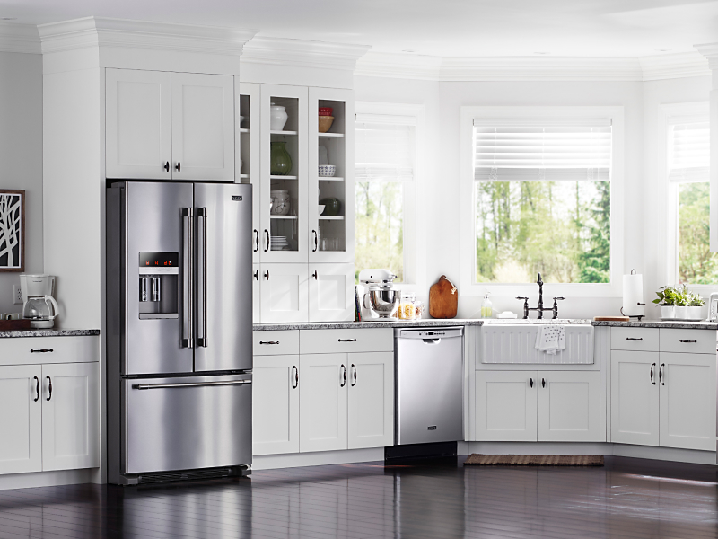 Stainless steel appliances in open kitchen with white cabinets