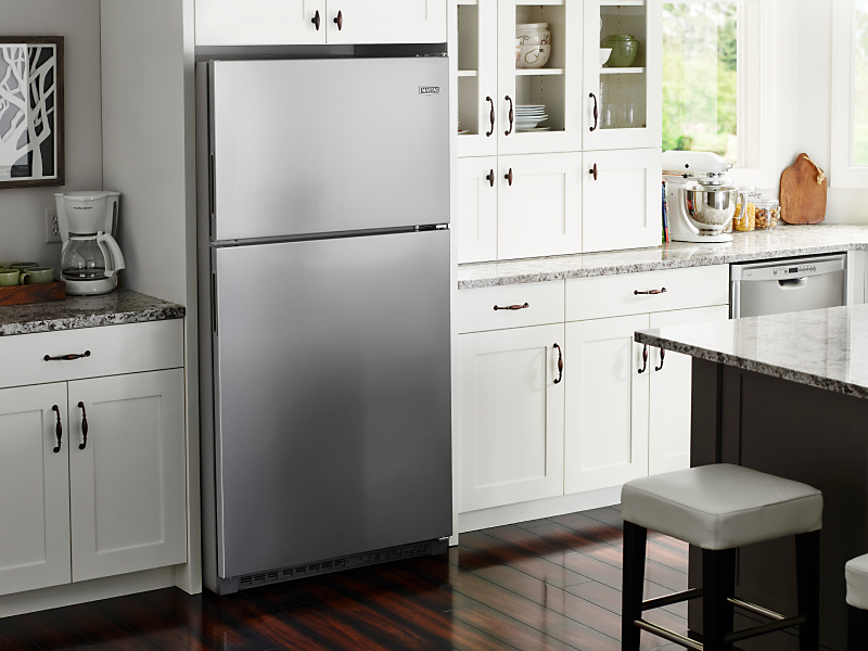 Top-freezer refrigerator in kitchen with white cabinets and granite countertops