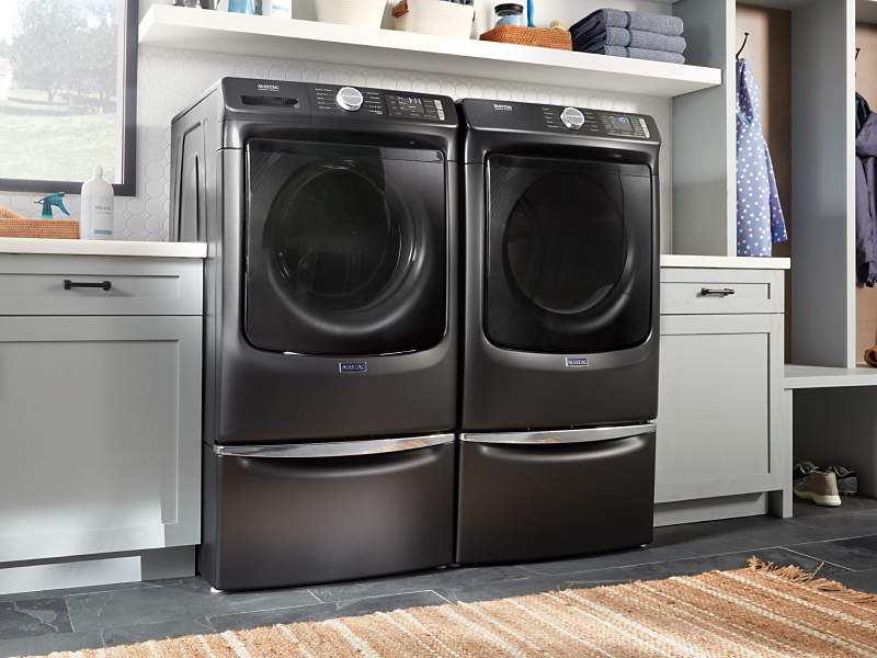 Maytag® front load washer and dryer set on laundry pedestals 