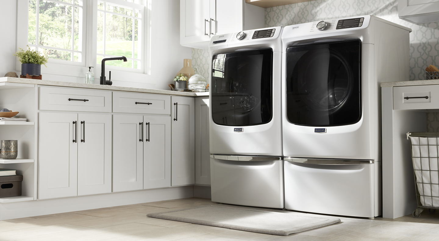 Side-by-side washing machine and dryer in white on pedestals