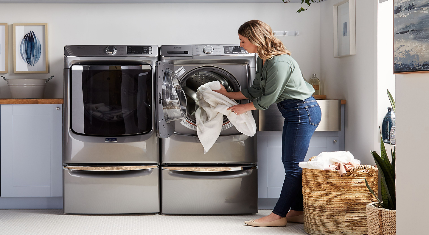 User adding towels to front load washing machine