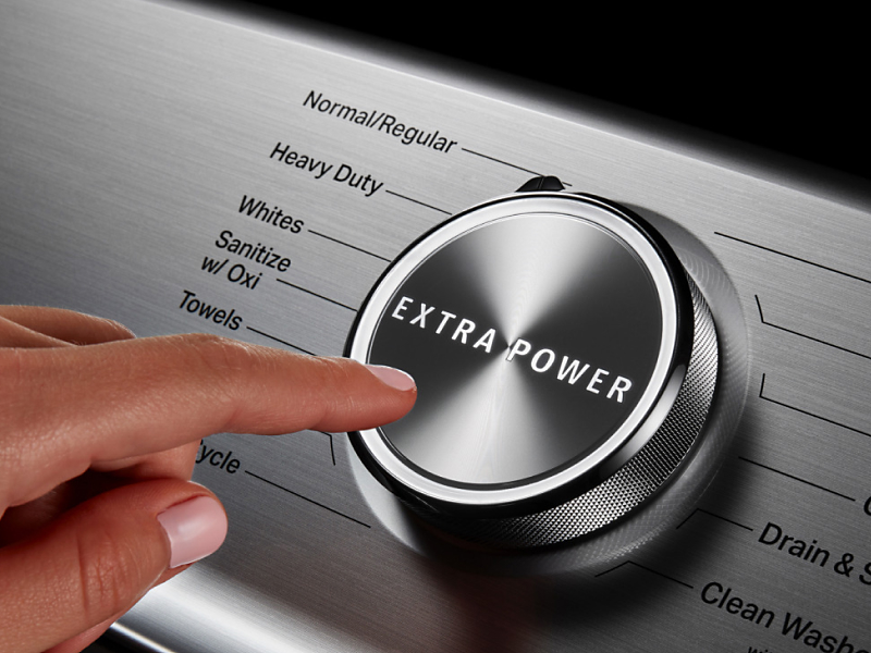 Finger pressing extra power button on washing cycle control panel Finger pressing extra power button on washing cycle control panel