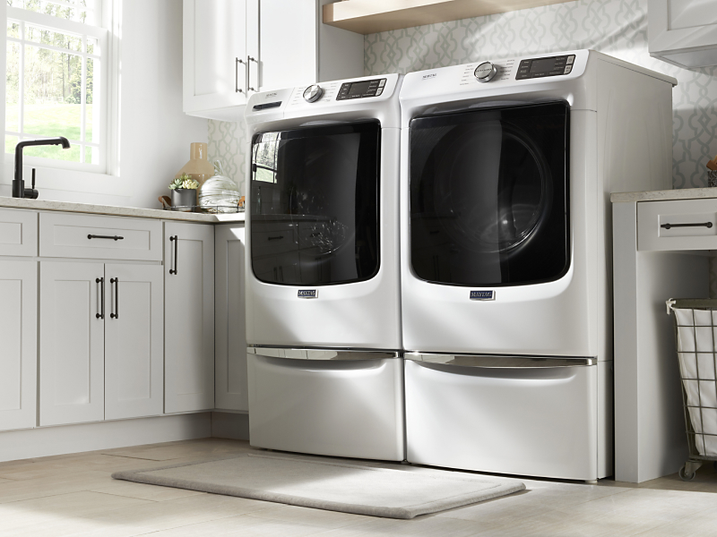 Side-by-side washing machine and dryer in white on pedestals Side-by-side washing machine and dryer in white on pedestals