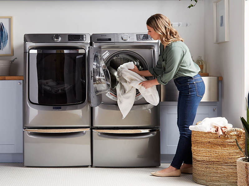 User adding towels to front load washing machine User adding towels to front load washing machine