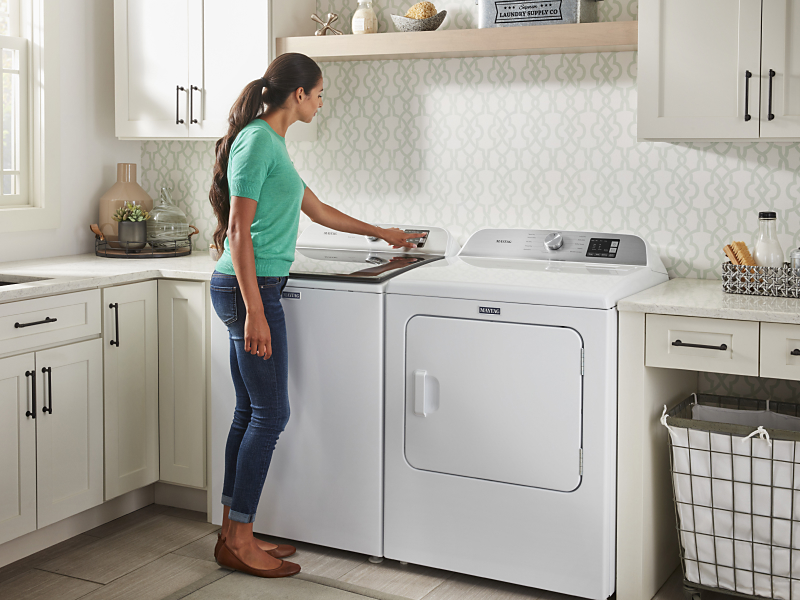User pressing button on white top load washing machine User pressing button on white top load washing machine