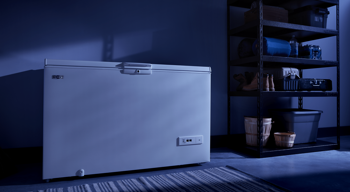 A white Maytag® chest freezer in a dark room