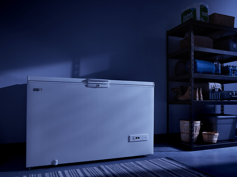 A white Maytag® chest freezer in a dark room