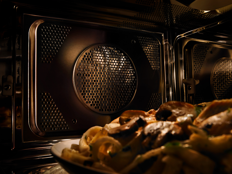A close-up of a Maytag® convection microwave interior with a plate of pasta