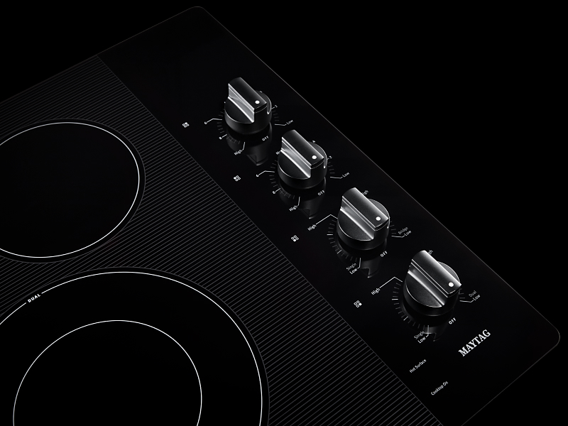  Close-up of electric cooktop with black knob controls