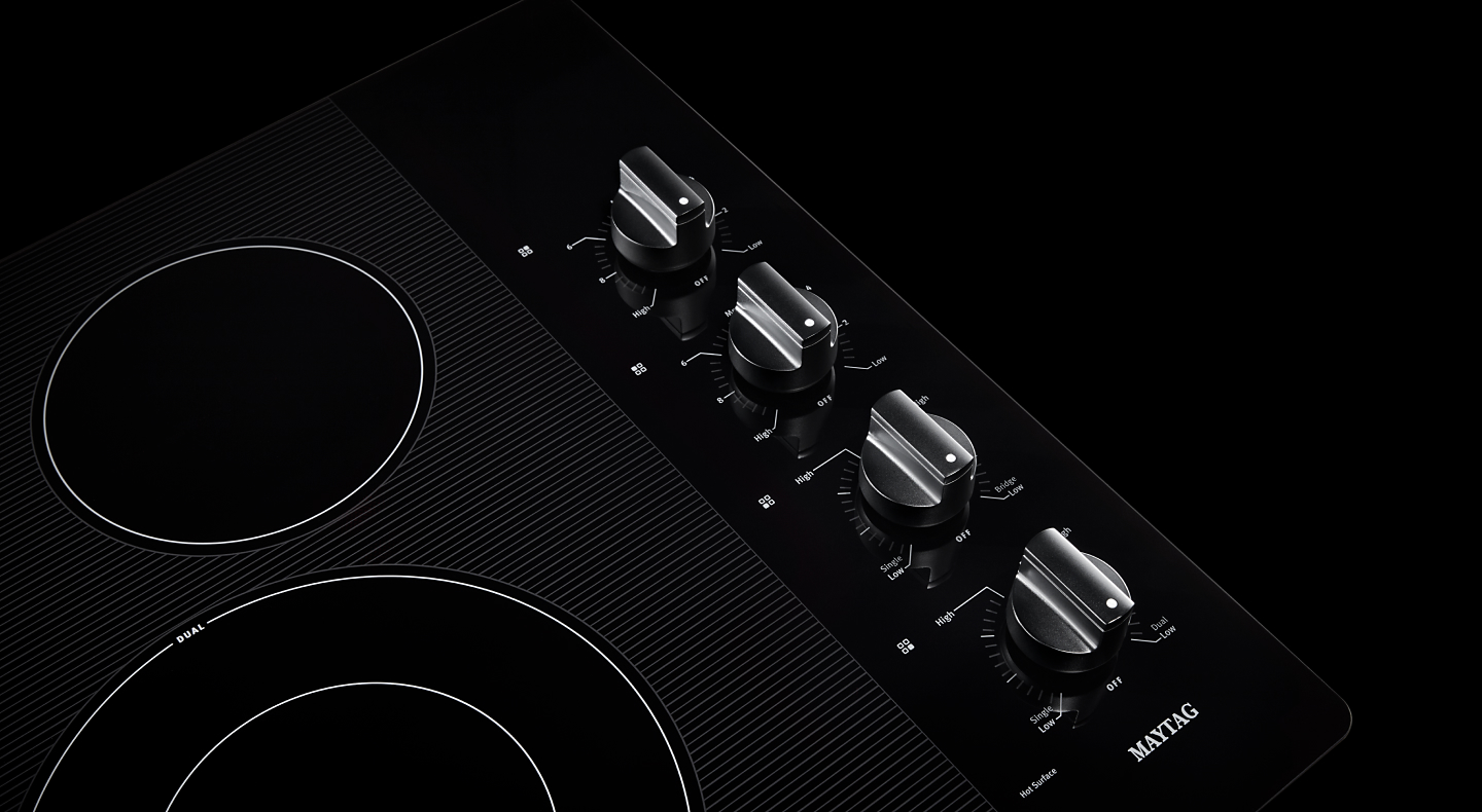  Close-up of electric cooktop with black knob controls