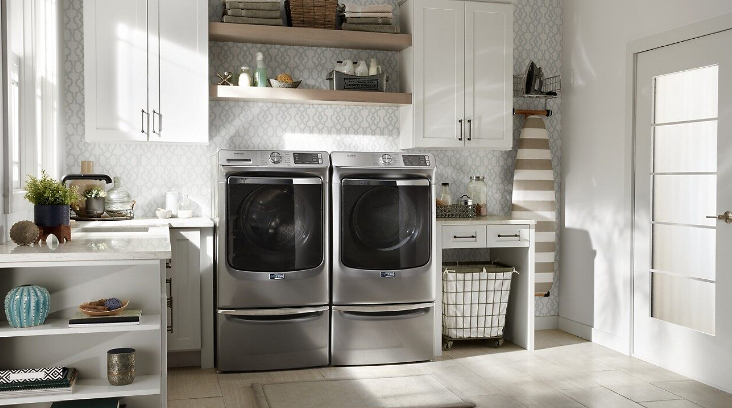 Maytag® washer and dryer on laundry pedestals in bright laundry room