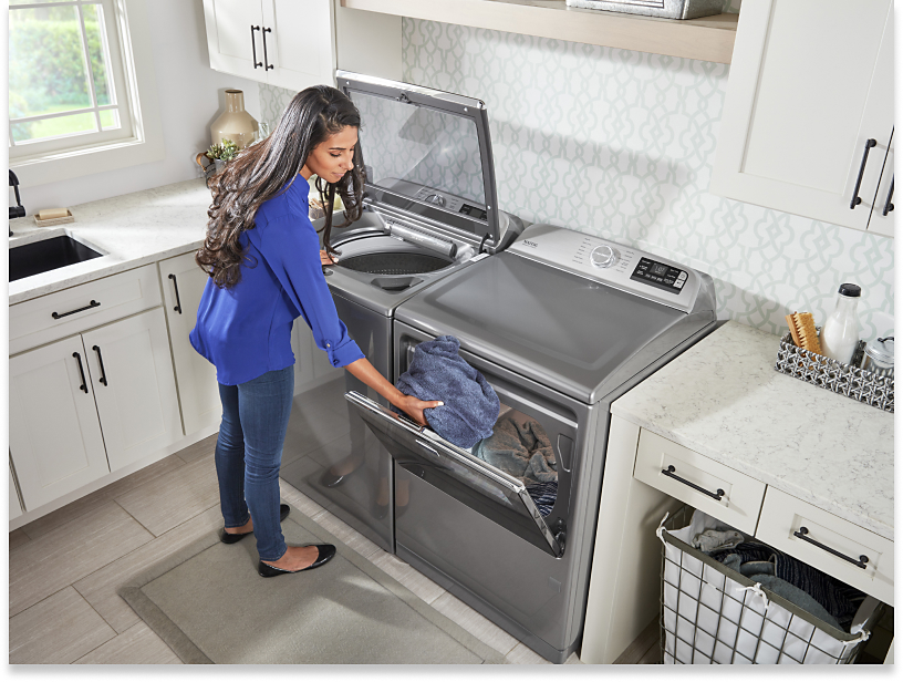 Person transferring wet clothes from a top-load washer to the dryer