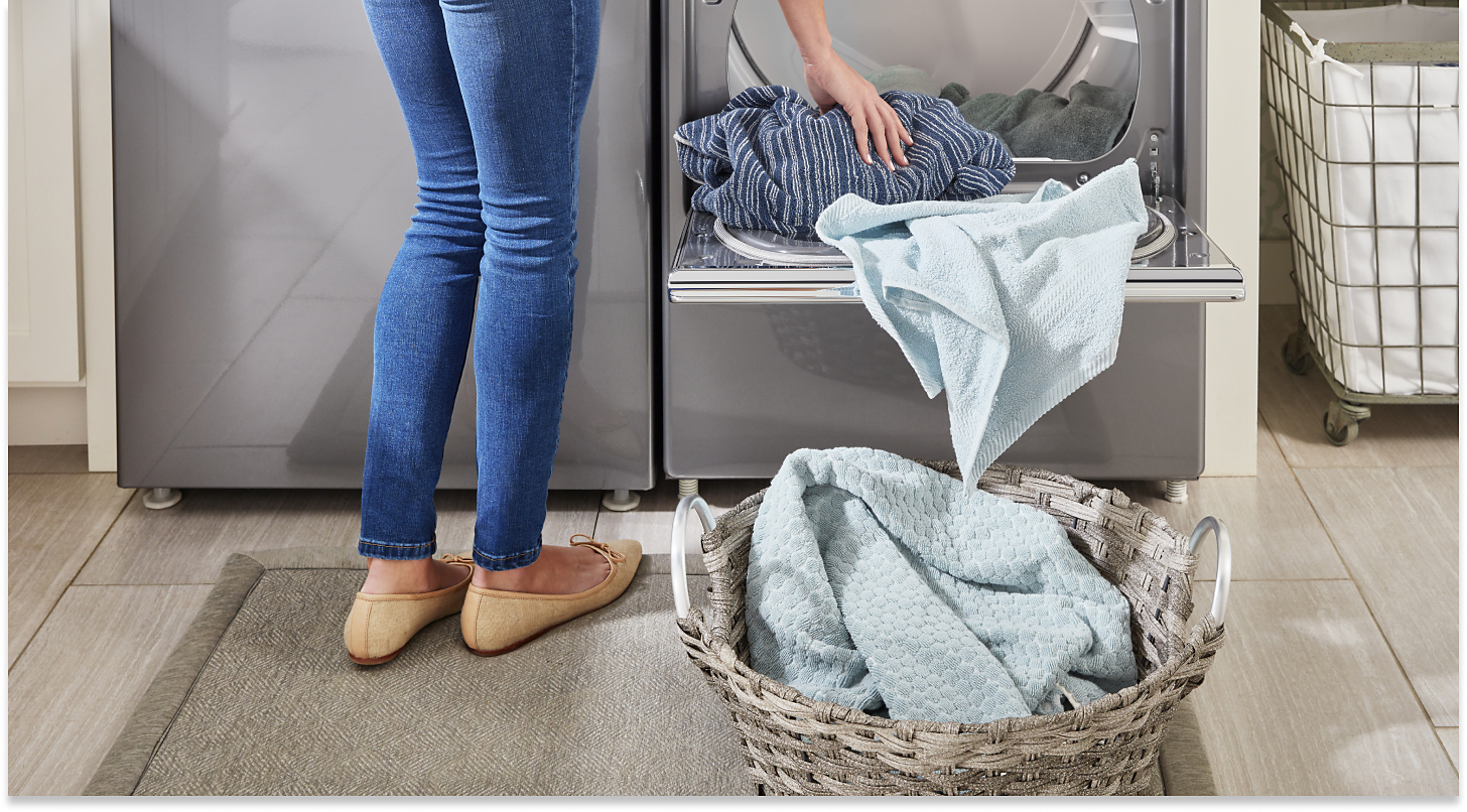 Person unloading clothes from the dryer into a laundry basket