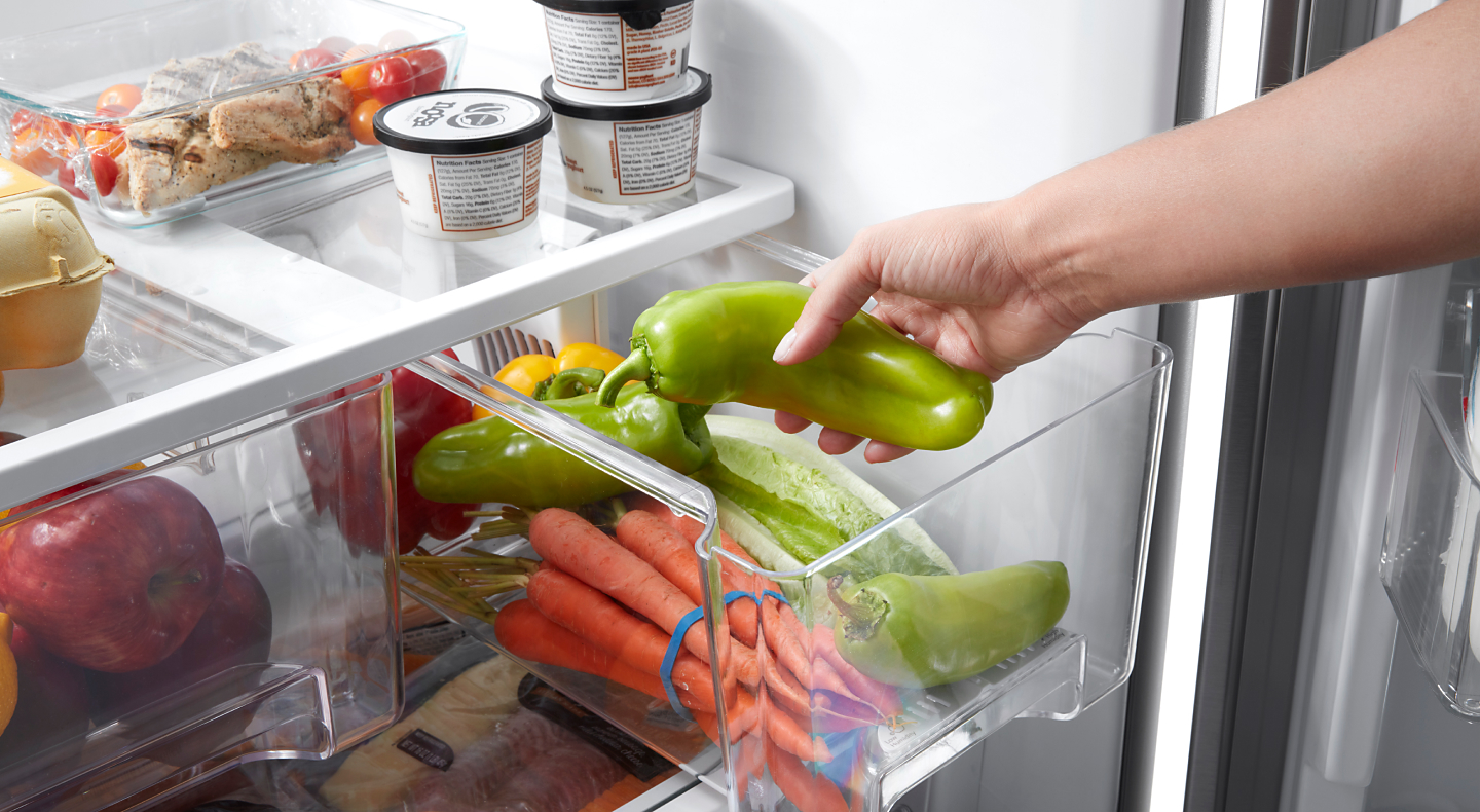 Person placing peppers into a crisper drawer