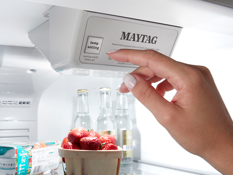 Person selecting temperature settings inside a Maytag® refrigerator