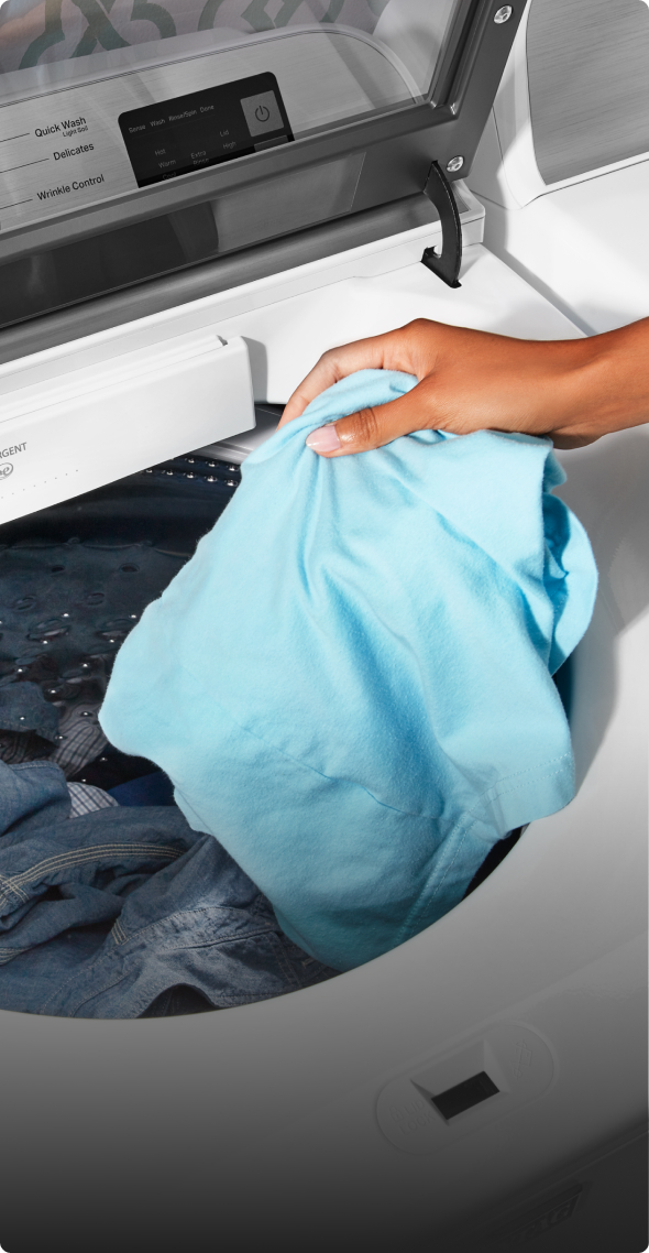 Adding clothes to the washer.