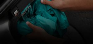 Hand rinsing a shirt in a stream of water.