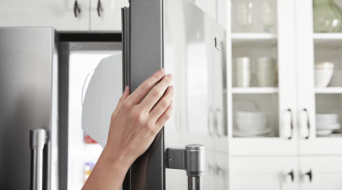 A person opens the door of a counter-depth fridge.