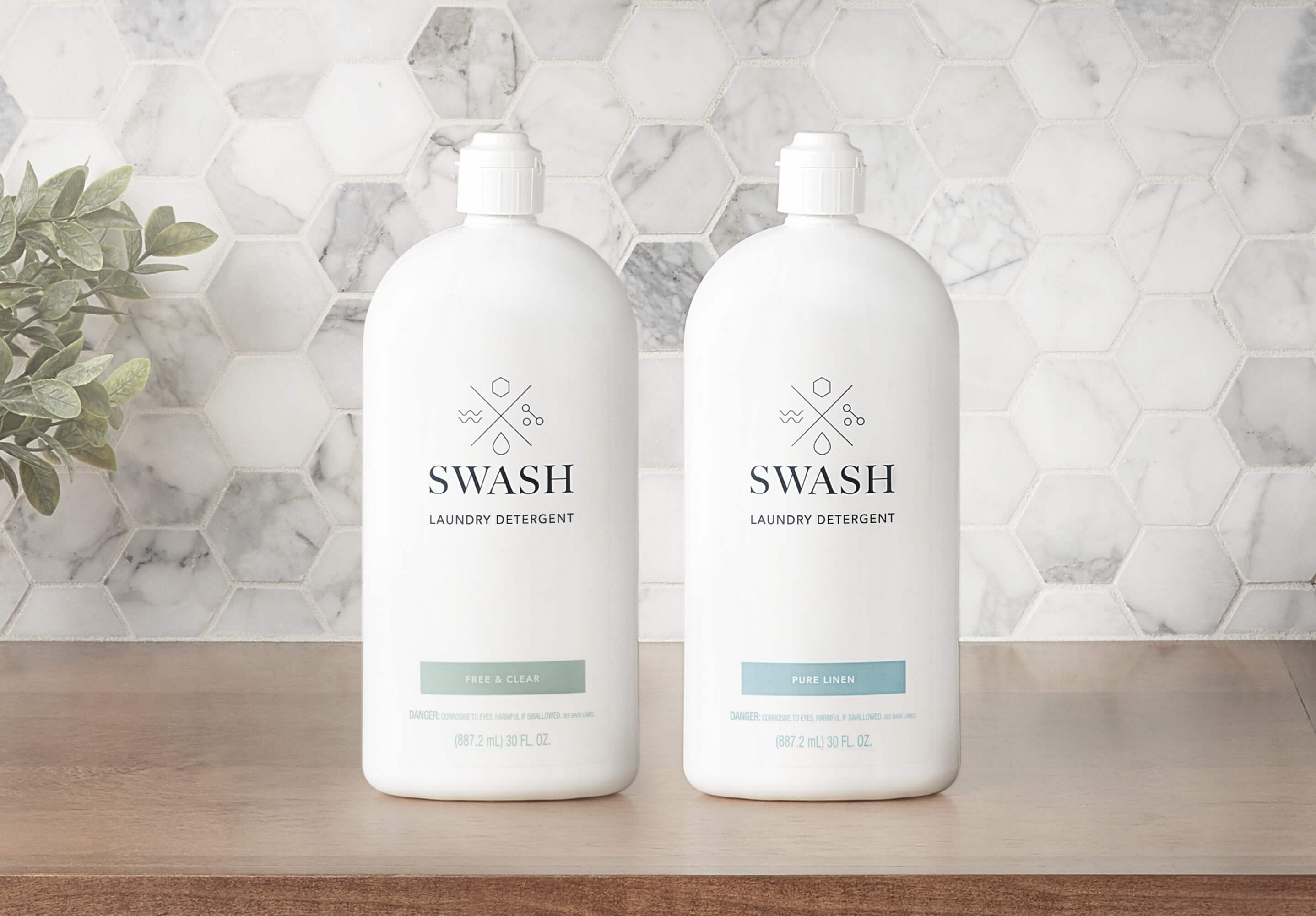 Swash Pure Linen and Free and Clear Laundry Detergent in sleek white bottles on a wooden surface