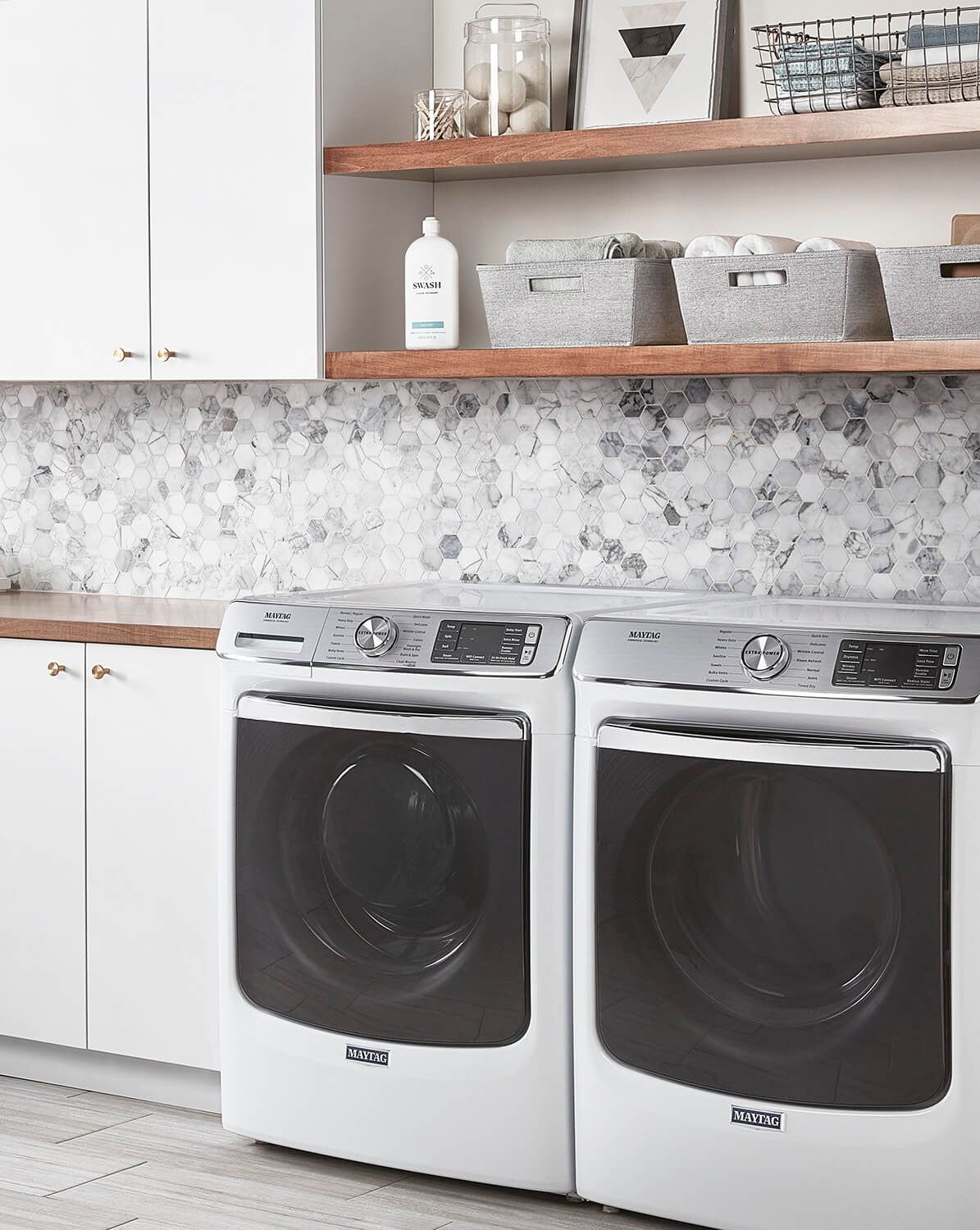 A light and airy laundry room with front loading machines and open shelving