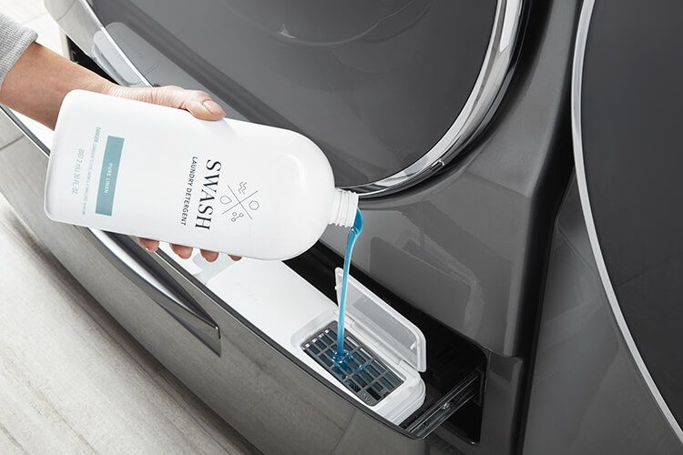 Woman dispensing Swash Pure Linen laundry detergent into her bulk dispensing washing machine