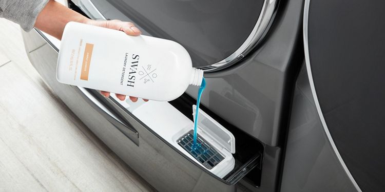 Woman dispensing Swash Simply Sunrise laundry detergent into her bulk dispensing washing machine