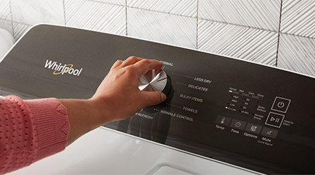 A person adjusts the dial on a Whirlpool dryer.