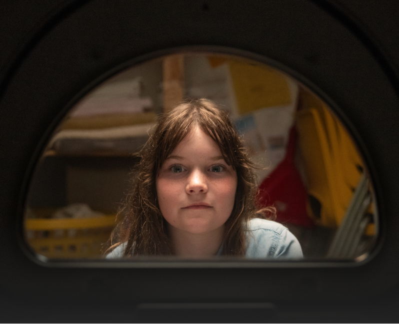A child’s face framed by a dryer opening