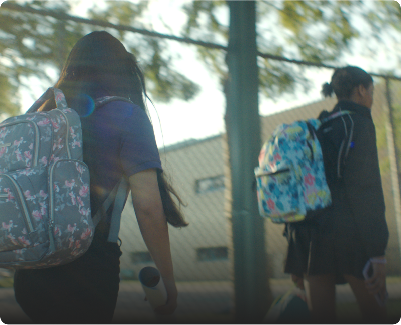 Kids with backpacks walk outside a school