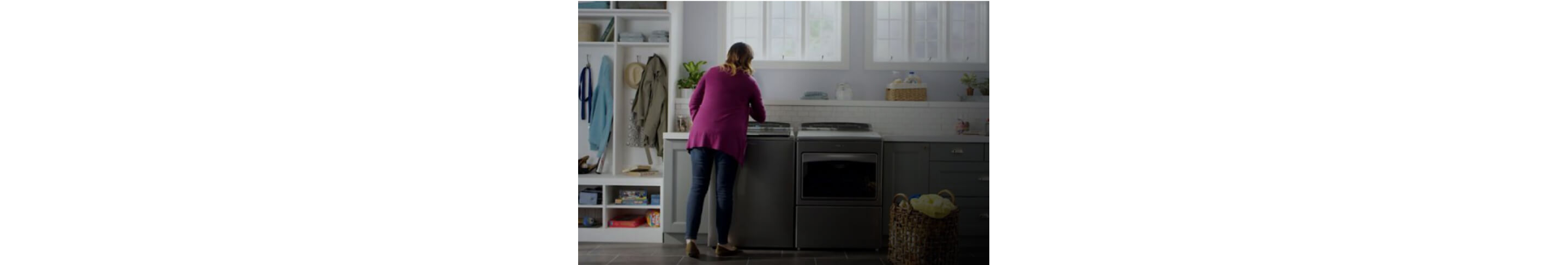 一名妇女与惠而浦®顶负载洗衣机和烘干机在洗衣房互动