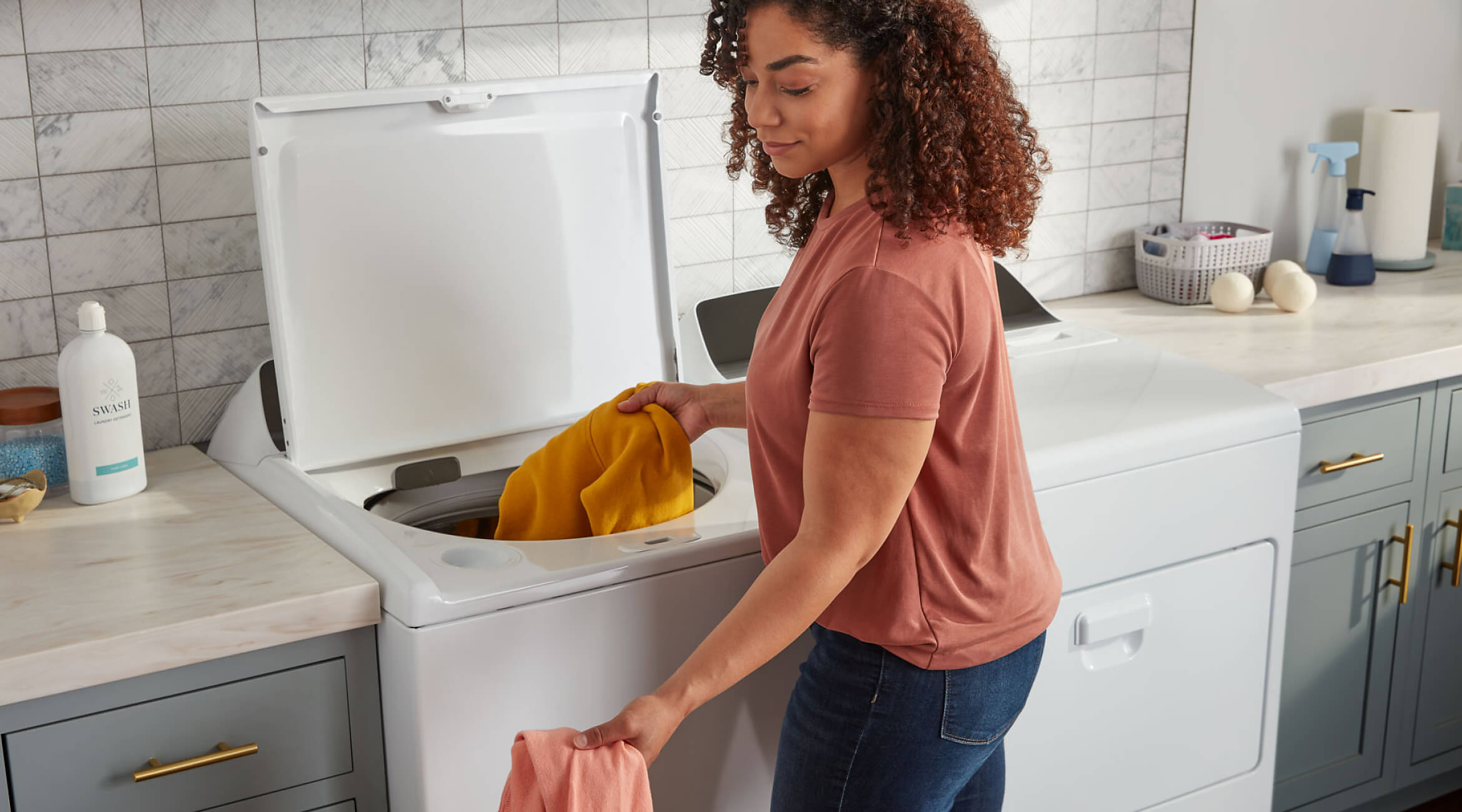 Person loading laundry into a Whirlpool® Top Load Washer