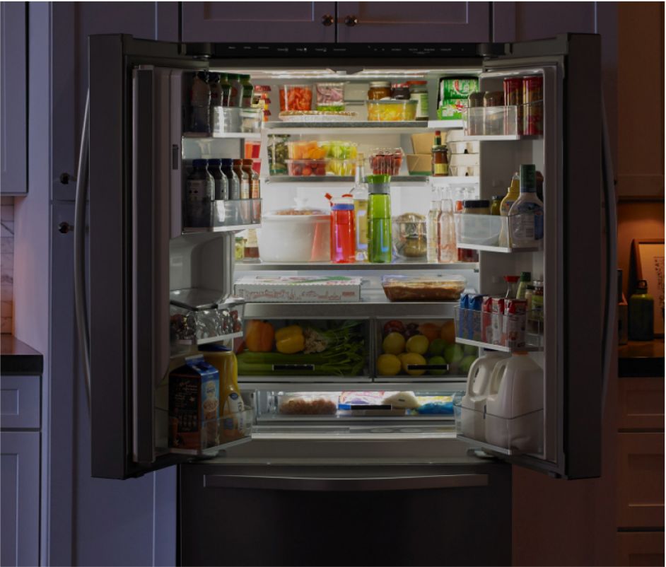 An open counter-depth refrigerator stocked with food and drinks