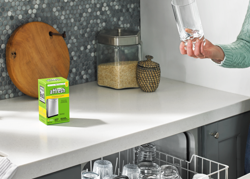 Affresh® cleaner next to an opened dishwasher.