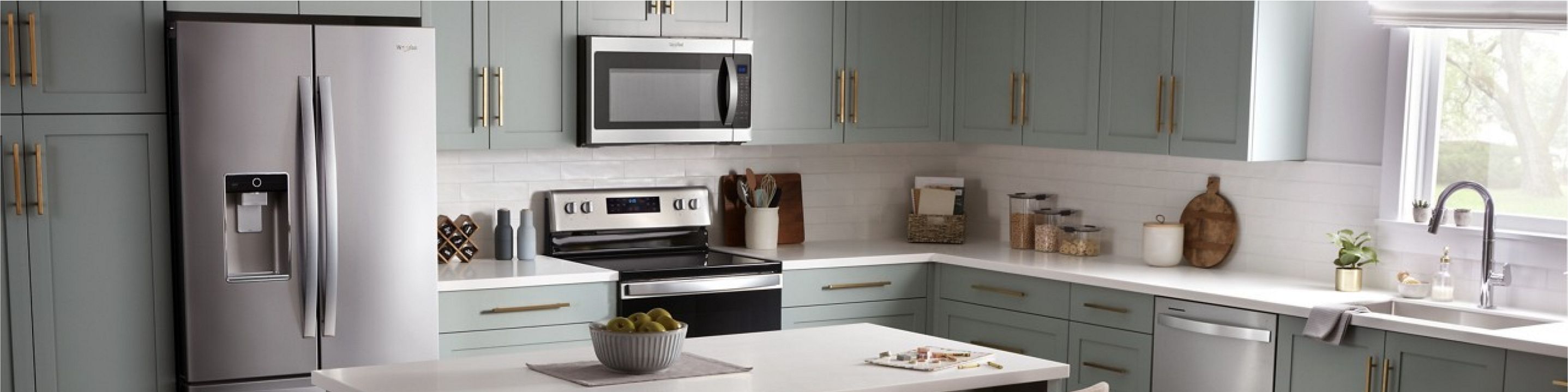 A kitchen with sage green cabinets and an island with three counter height chairs
