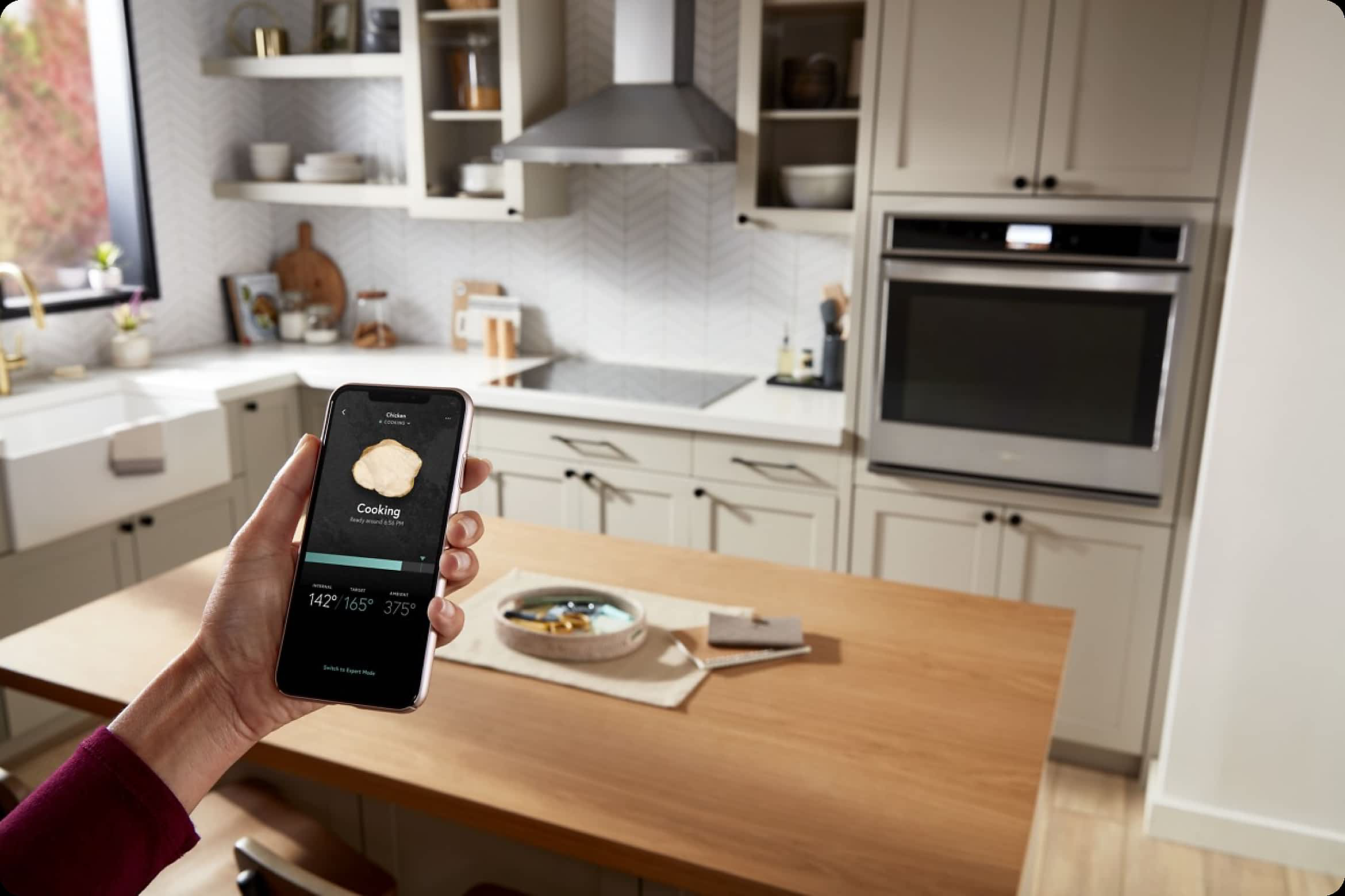 Hands control a Whirlpool® Smart Wall Oven via the Whirlpool® App